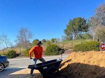Man shoveling dirt into a wheelbarrow